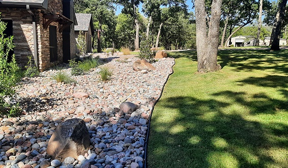 Stone-lined landscape bed and freshly maintained lawn